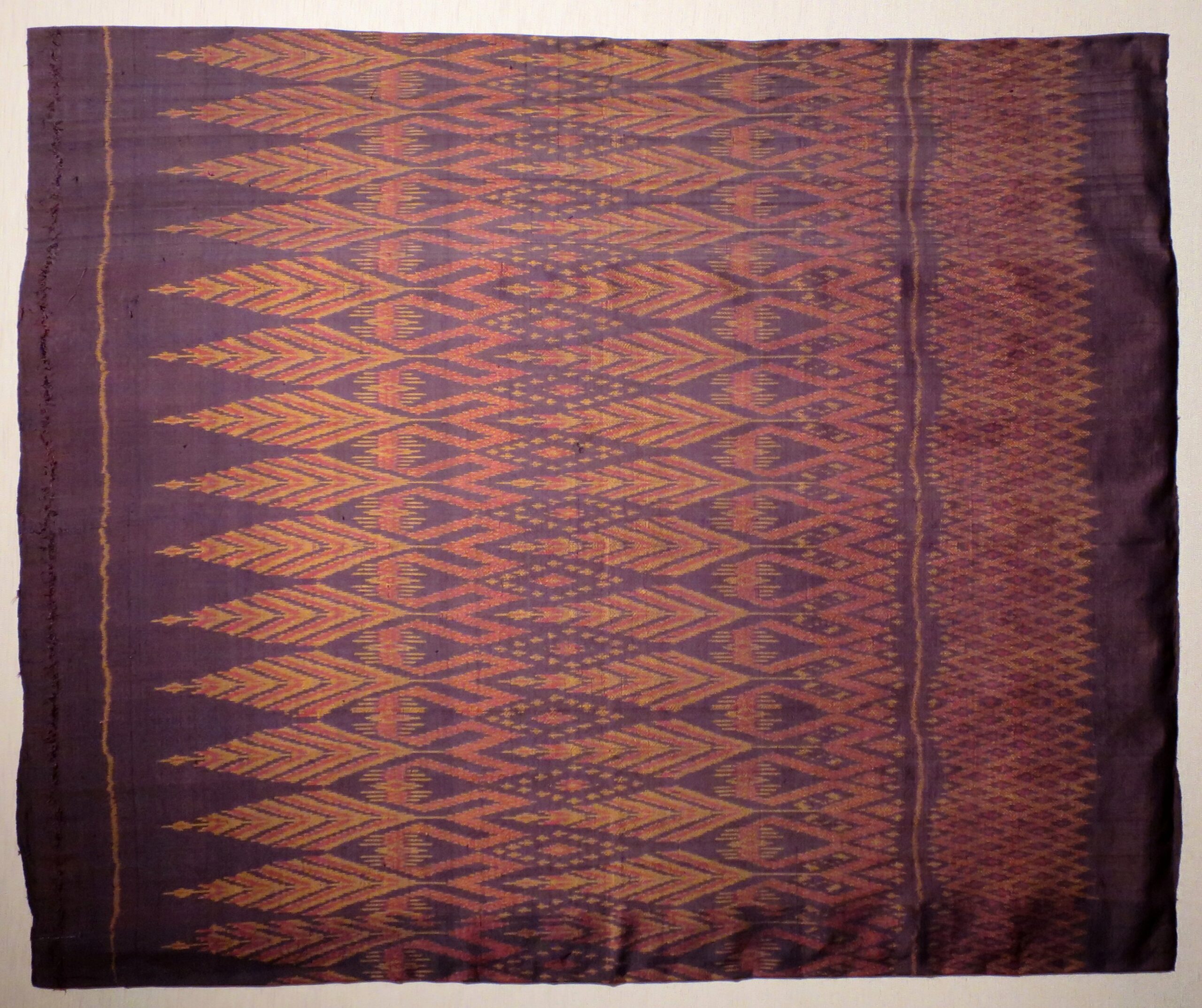 Thai silk sarong with red and gold weft-ikat motifs on a deep purple ground.